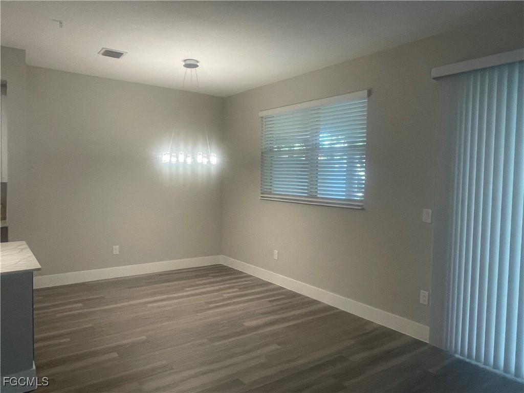 7044 Ambrosia Lane, Unit 103 Naples, FL 34119 - Photo 19 of 20 an empty room with wooden floor and windows