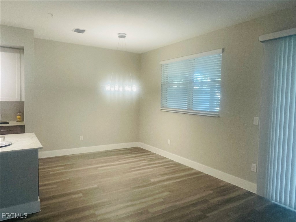 7044 Ambrosia Lane, Unit 103 Naples, FL 34119 - Photo 20 of 20 a view of an empty room with wooden floor and a window