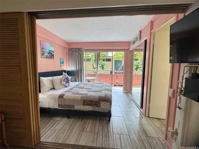 a bedroom with a bed wooden floor and a flat tv screen