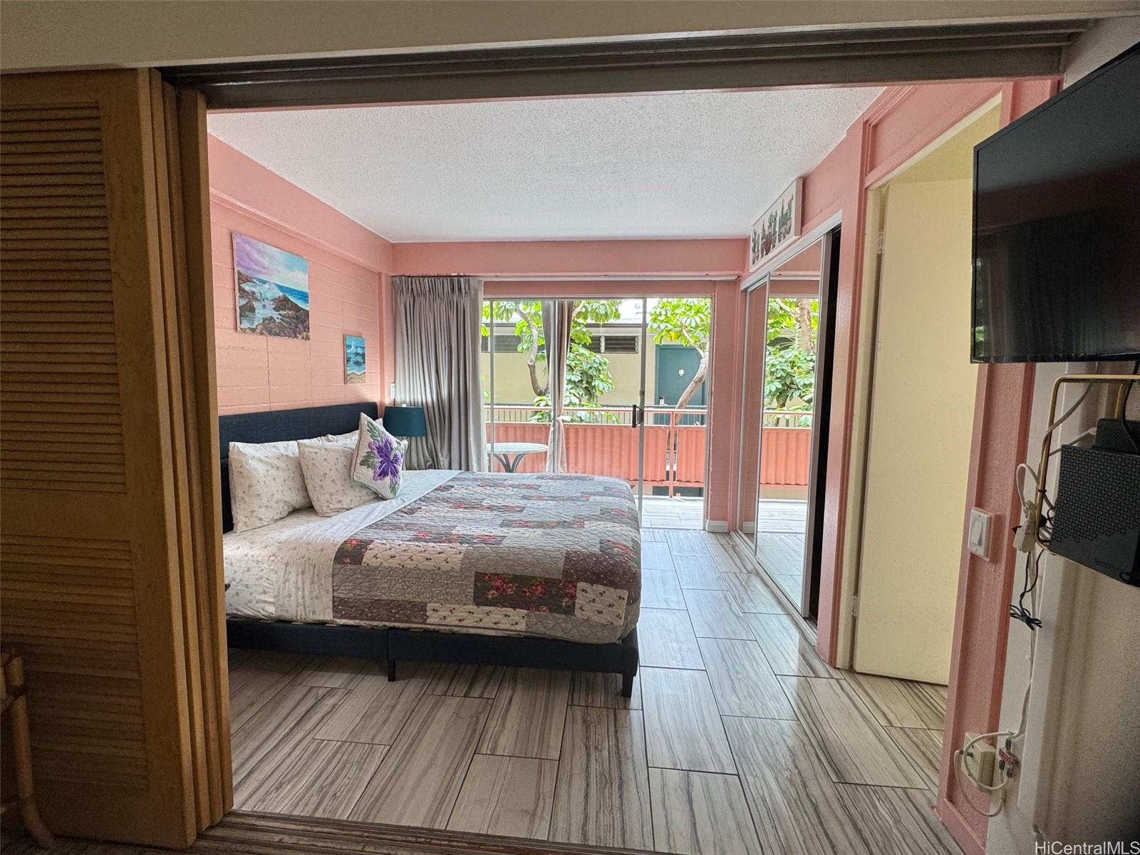 417 Nohonani Street, Unit 410 Honolulu, HI 96815 - Photo 2 of 20 a bedroom with a bed wooden floor and a flat tv screen
