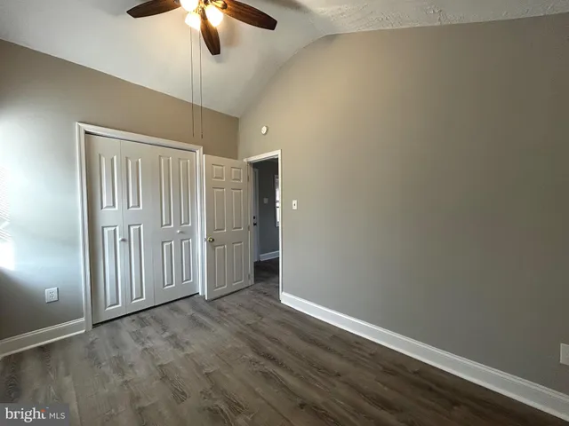 an empty room with wooden floor fan and window
