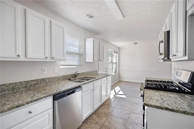 a kitchen with stainless steel appliances granite countertop a sink and a stove