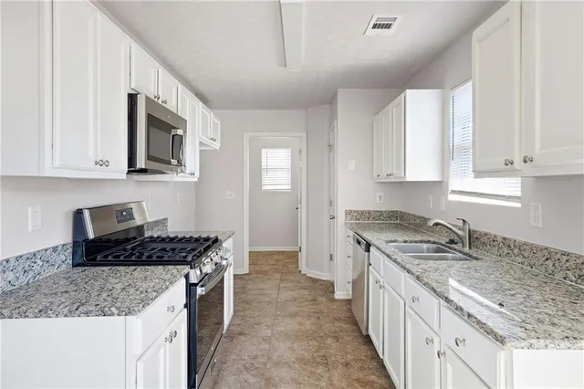 a kitchen with granite countertop a sink stove and cabinets