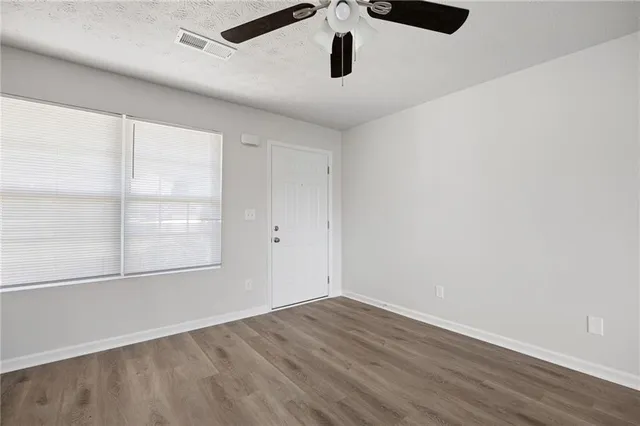 an empty room with wooden floor and windows