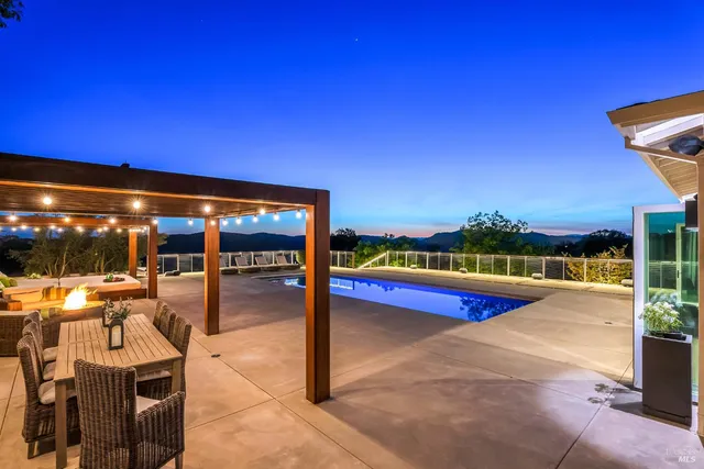 a dining room with wooden floor a chandelier a glass table and chairs