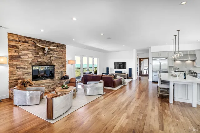 a living room with furniture large window and wooden floor