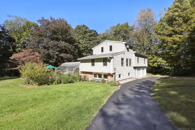 a view of a white house with a big yard and large trees