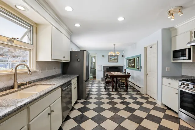 a kitchen with stainless steel appliances granite countertop a sink a stove a refrigerator and island with wooden cabinets