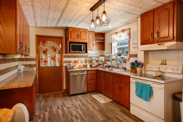 a kitchen with stainless steel appliances granite countertop wooden cabinets a stove top oven a sink and dishwasher