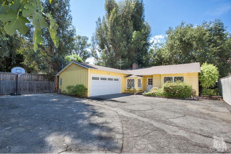 a view of a house with a yard and large trees