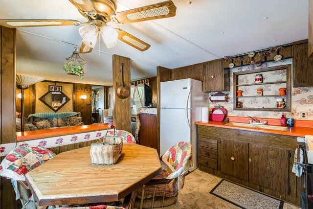 a dining room with furniture and a chandelier fan