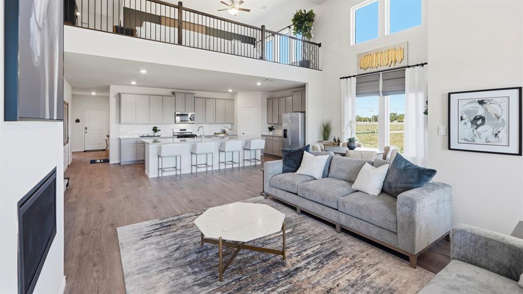 4197 Waldron Trail Forney, TX 75126 - Photo 13 of 25 Open-concept living space featuring wood-finish flooring, a contemporary fireplace, and a two-story ceiling