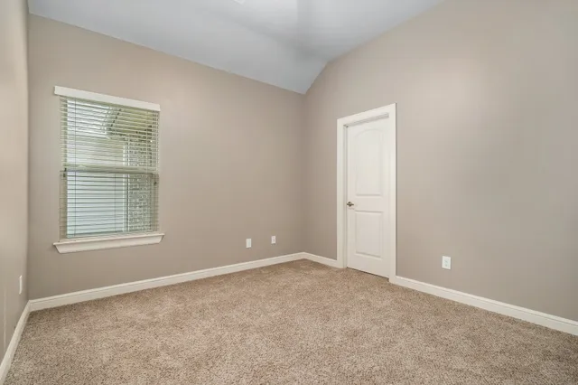 an empty room with chandelier fan and windows