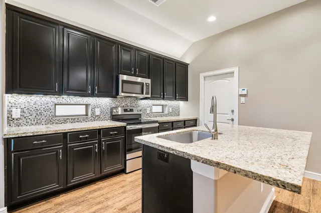 a kitchen with granite countertop stainless steel appliances and wooden cabinets