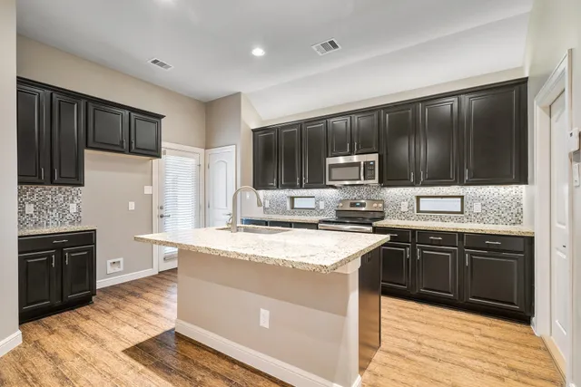 a view of kitchen with microwave oven stove and white cabinets with wooden floor