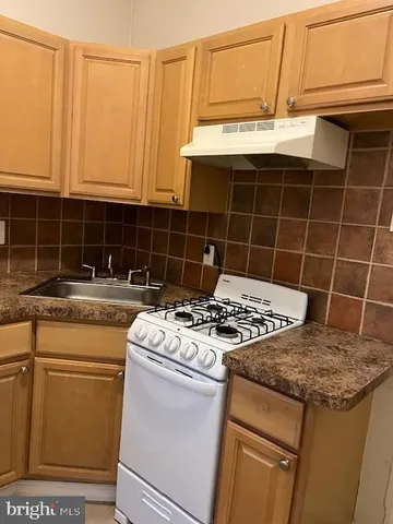 a kitchen with granite countertop a stove sink and cabinets