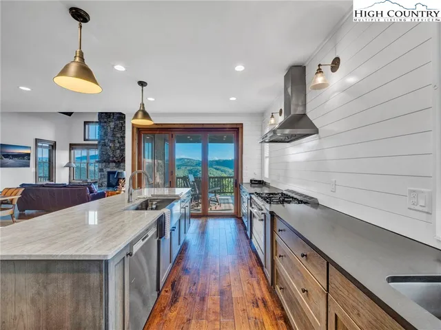 a kitchen with granite countertop a stove a sink a refrigerator and wooden floor