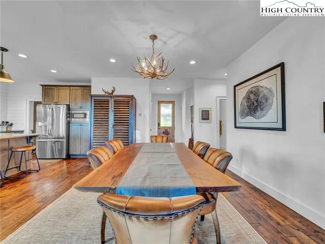 a living room with a dining table and paintings on the wall with wooden floor