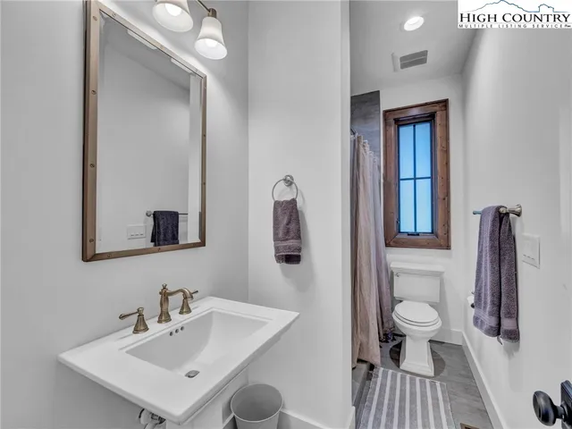 a bathroom with a sink a toilet and a mirror