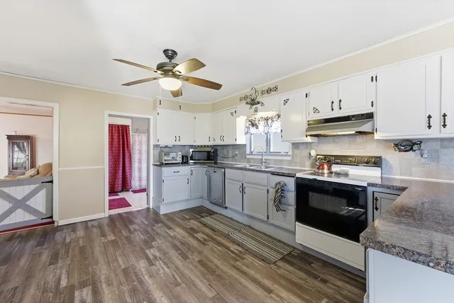 a kitchen with granite countertop a refrigerator oven a sink dishwasher and white cabinets with wooden floor