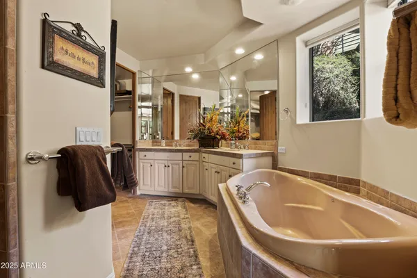 a bathroom with a tub a sink and a large mirror