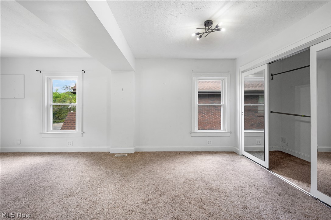 371 Merriman Road Akron, OH 44303 - Photo 13 of 27 Carpeted room with white walls, two windows, and a modern multi-bulb ceiling fixture
