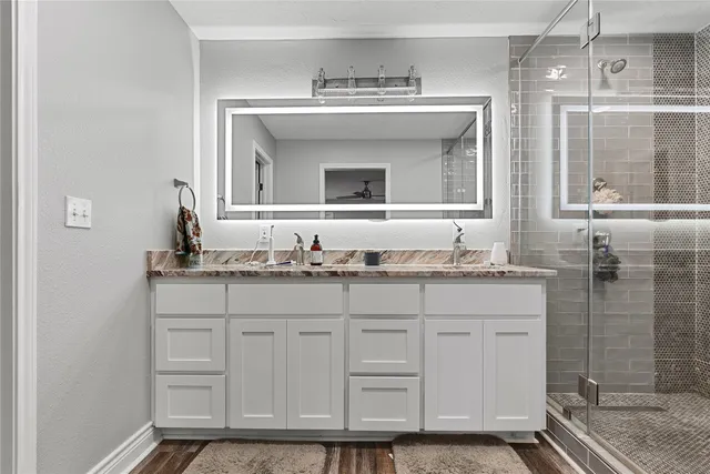 a bathroom with a granite countertop sink two mirror and a shower
