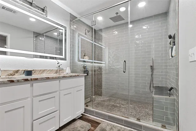 a bathroom with a granite countertop sink mirror and shower