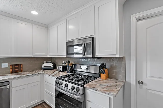 a kitchen with white cabinets and appliances