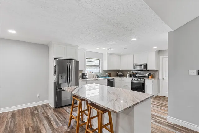 a kitchen with stainless steel appliances granite countertop a kitchen island hardwood floor sink stove and refrigerator