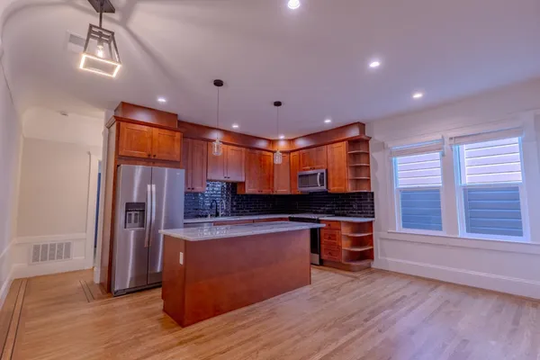 a large kitchen with stainless steel appliances granite countertop a stove and a wooden floors