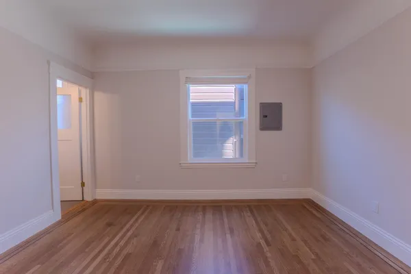 a view of an empty room with wooden floor and a window