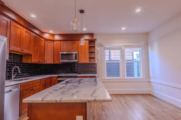 a kitchen with kitchen island granite countertop a stove and a sink