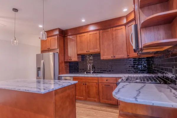 a kitchen with stainless steel appliances granite countertop a sink a stove and a wooden cabinets