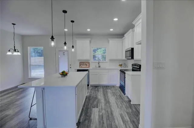 a kitchen with kitchen island a sink cabinets stainless steel appliances and a counter top space