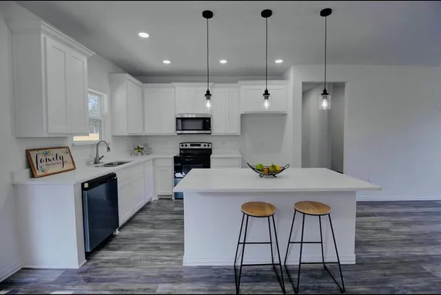 a kitchen with kitchen island a stove a table a sink cabinets and wooden floor