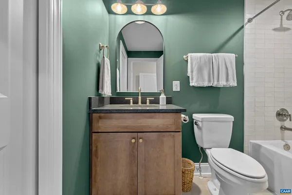 a bathroom with a granite countertop toilet sink and mirror