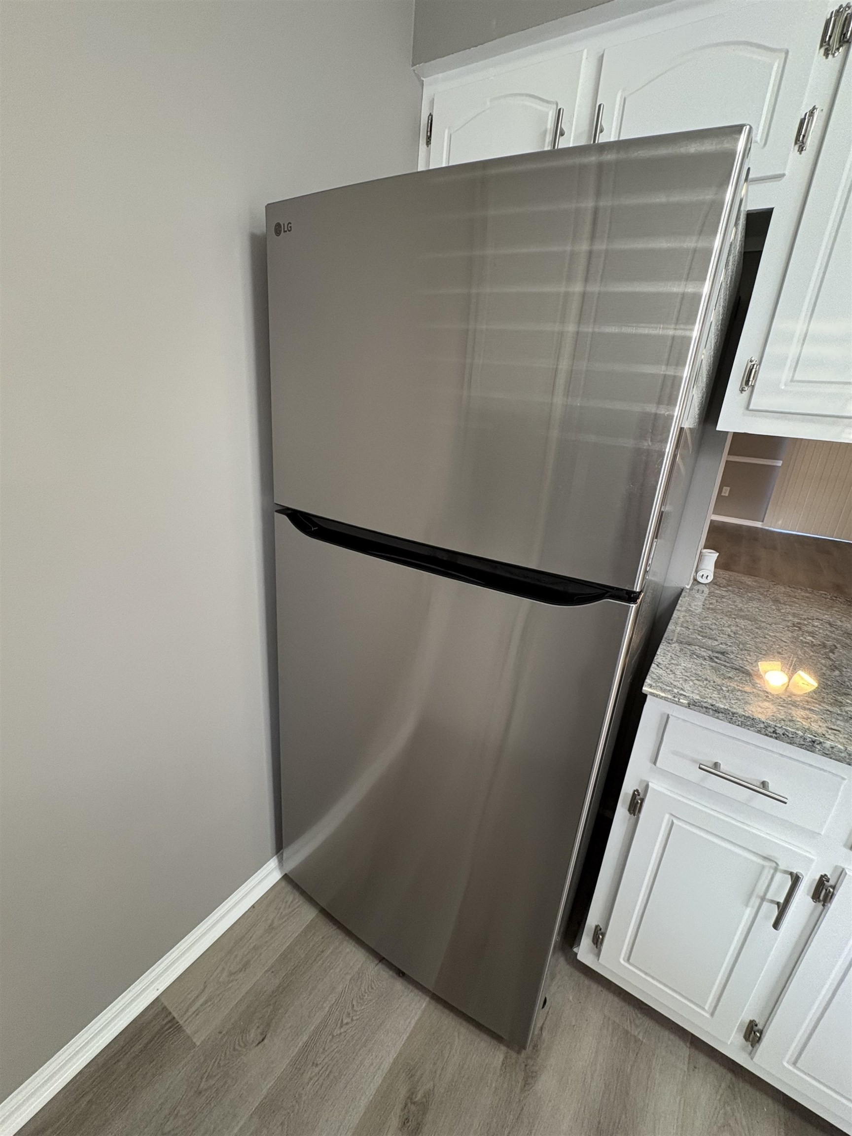 4641 Socastee Boulevard, Unit D1 Myrtle Beach, SC 29588 - Photo 11 of 12 Kitchen view of white cabinets, light stone counters, freestanding refrigerator, and light wood-style flooring