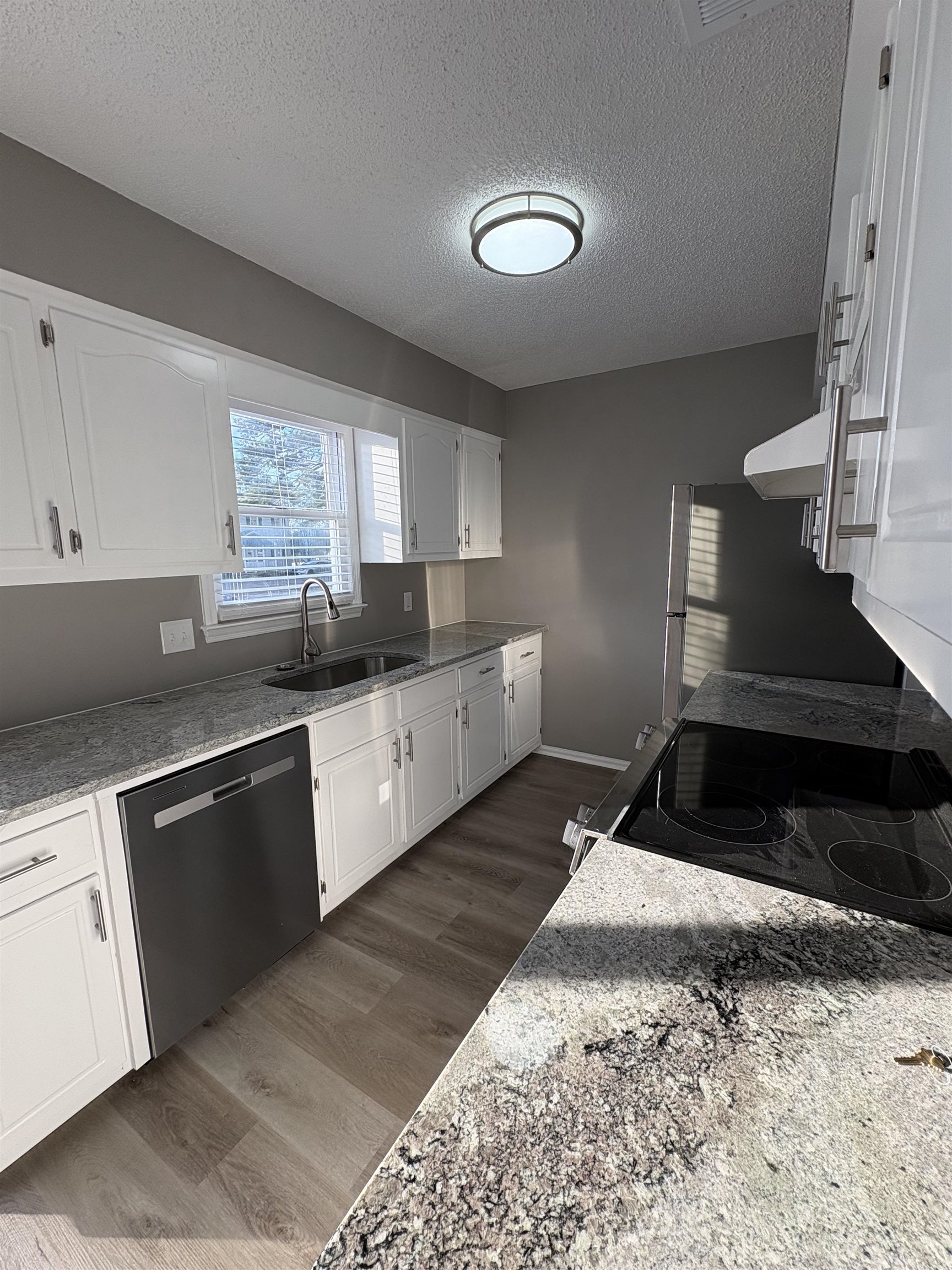 4641 Socastee Boulevard, Unit D1 Myrtle Beach, SC 29588 - Photo 3 of 12 Kitchen with light stone counters, white cabinetry, dark wood finished floors, stainless steel appliances, and a textured ceiling