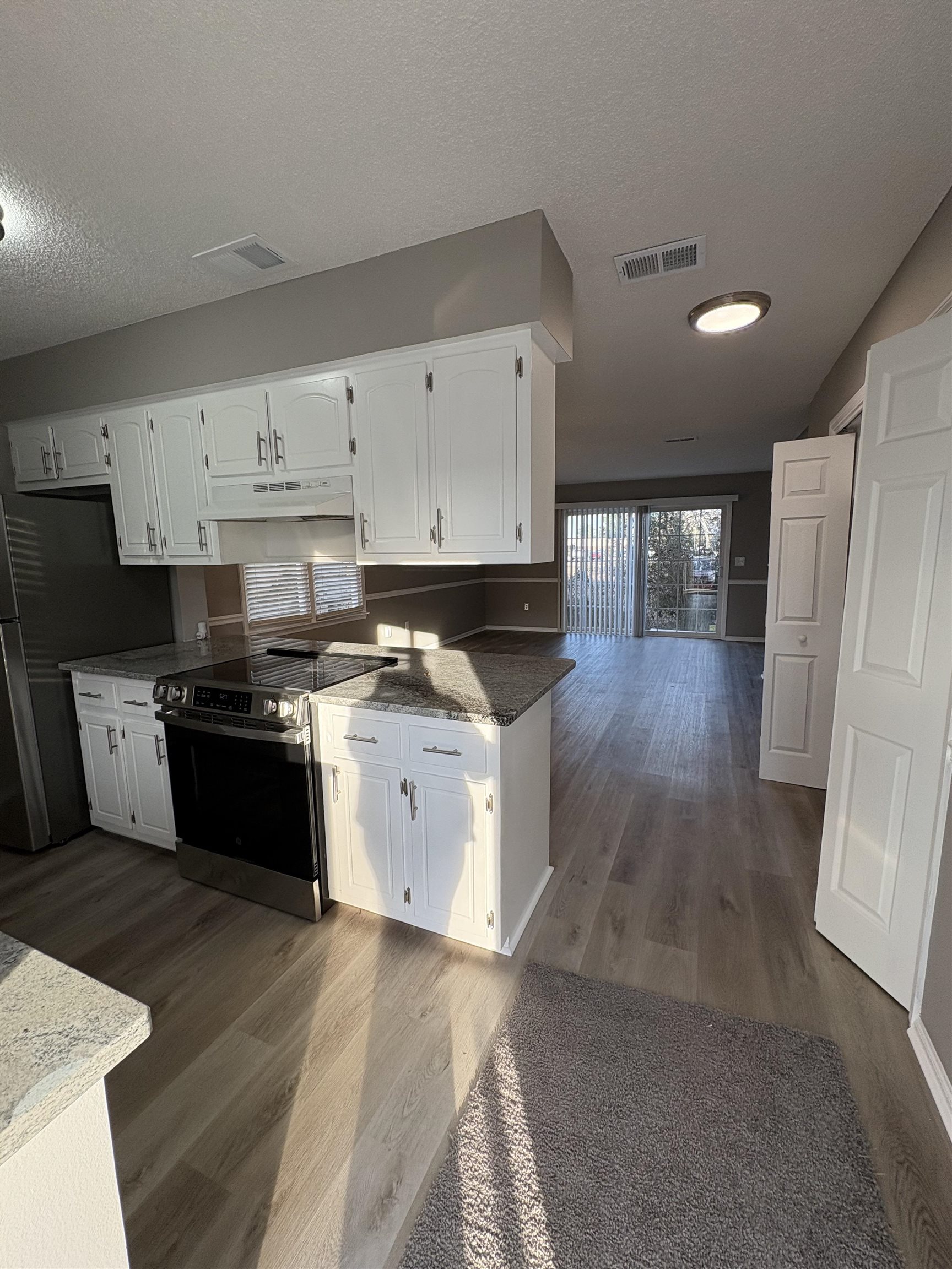 4641 Socastee Boulevard, Unit D1 Myrtle Beach, SC 29588 - Photo 4 of 12 Kitchen featuring white cabinets, stainless steel appliances, light wood-style flooring, under cabinet range hood, and dark stone countertops