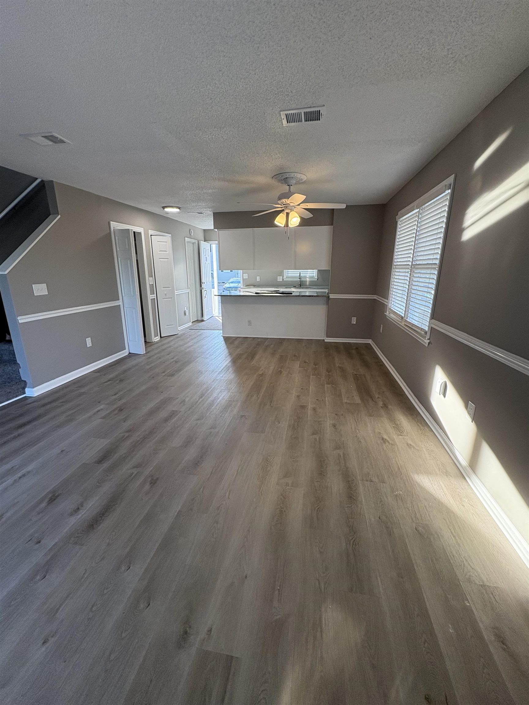 4641 Socastee Boulevard, Unit D1 Myrtle Beach, SC 29588 - Photo 7 of 12 Unfurnished living room featuring ceiling fan, dark wood finished floors, healthy amount of natural light, and a textured ceiling