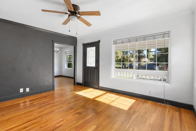 a view of an empty room with window and wooden floor