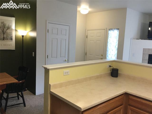 2095 Legacy Ridge View, Unit 112 Colorado Springs, CO 80910 - Photo 6 of 28 L shaped island with cabinets. Looking towards the front door. Coat entry closet too.