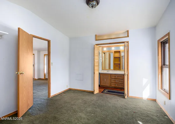 a view of an empty room with closet and a window
