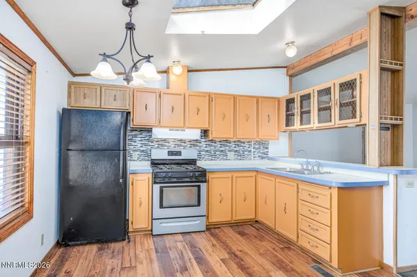 a kitchen with stainless steel appliances granite countertop a refrigerator a sink dishwasher a stove and white countertops with wooden floor