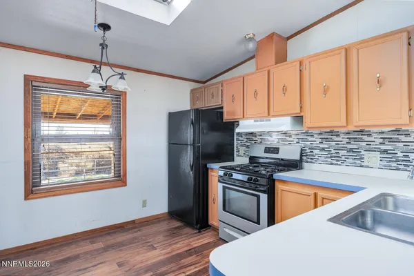 a kitchen with granite countertop a stove a sink dishwasher and a refrigerator with wooden floor