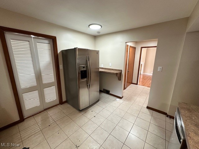 15959 Glynn Road Cleveland, OH 44112 - Photo 13 of 23 Kitchen featuring stainless steel fridge with ice dispenser, dark countertops, light tile patterned flooring, and dishwasher