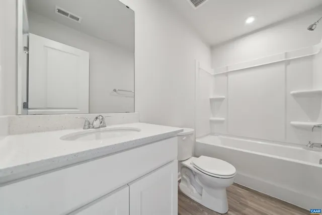 a bathroom with a granite countertop sink toilet a mirror and bathtub