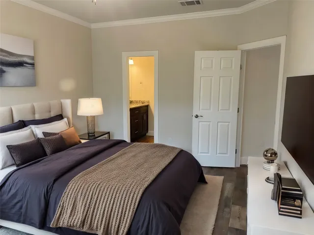 a bedroom with a bed and a flat tv screen on a dresser