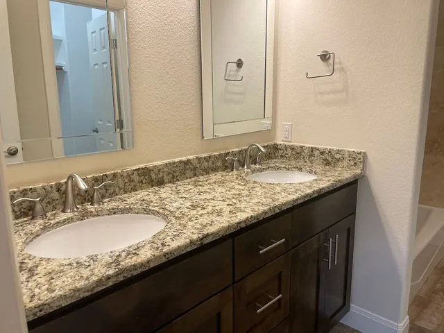 a bathroom with a granite countertop sink and a mirror